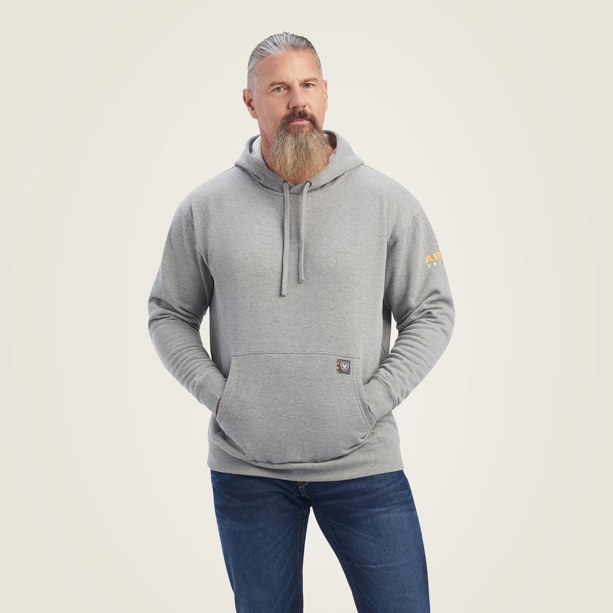 Man wearing a grey pullover hoodie with kangaroo pocket and Ariat logo on sleeve