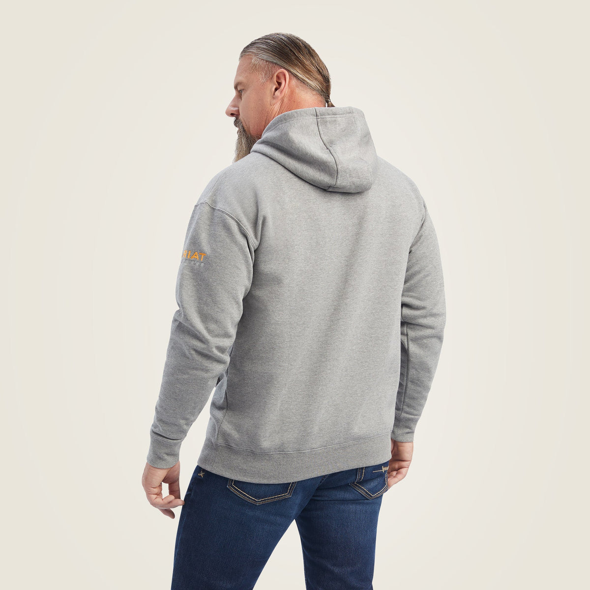 Man wearing grey pullover hoodie shown from the back with Ariat logo on sleeve