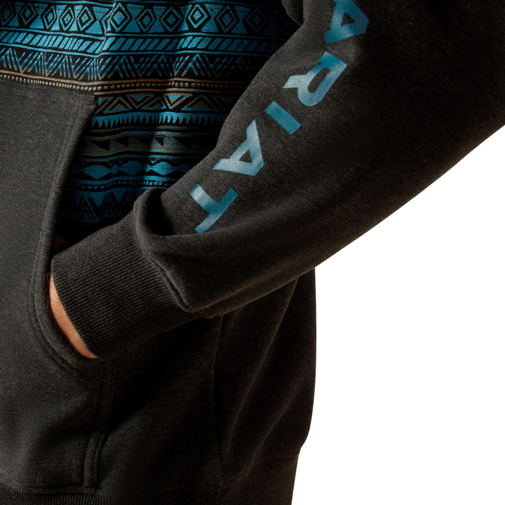 Close-up detail of Ariat men's black hoodie sleeve with turquoise Aztec pattern and logo
