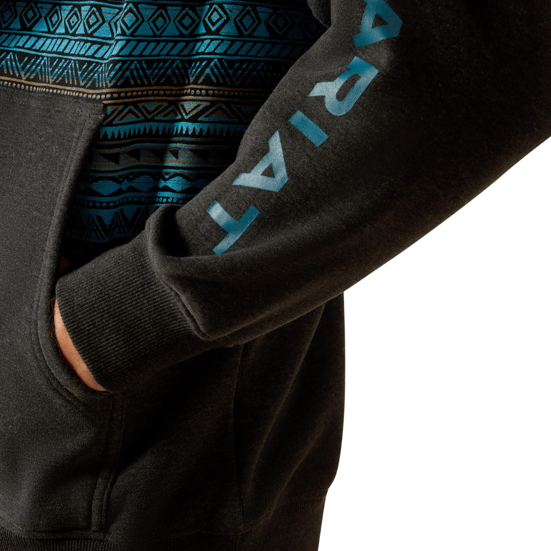 Close-up detail of Ariat men's black hoodie sleeve with turquoise Aztec pattern and logo