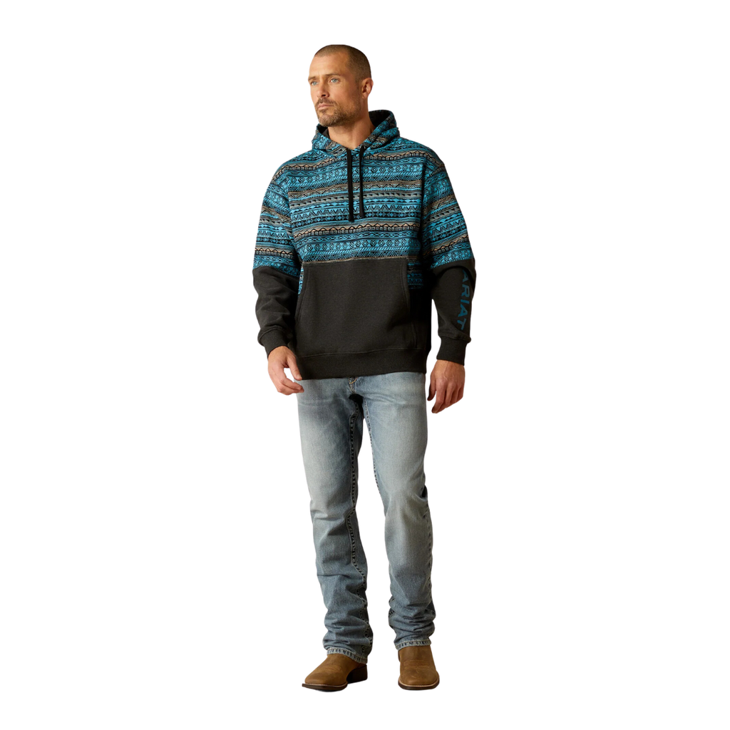Man wearing a color block hoodie with turquoise Aztec print upper and dark lower half