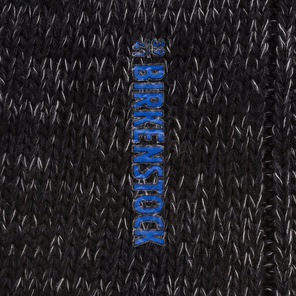 Close-up detail of black knit Birkenstock sock showing brand logo label with size markings