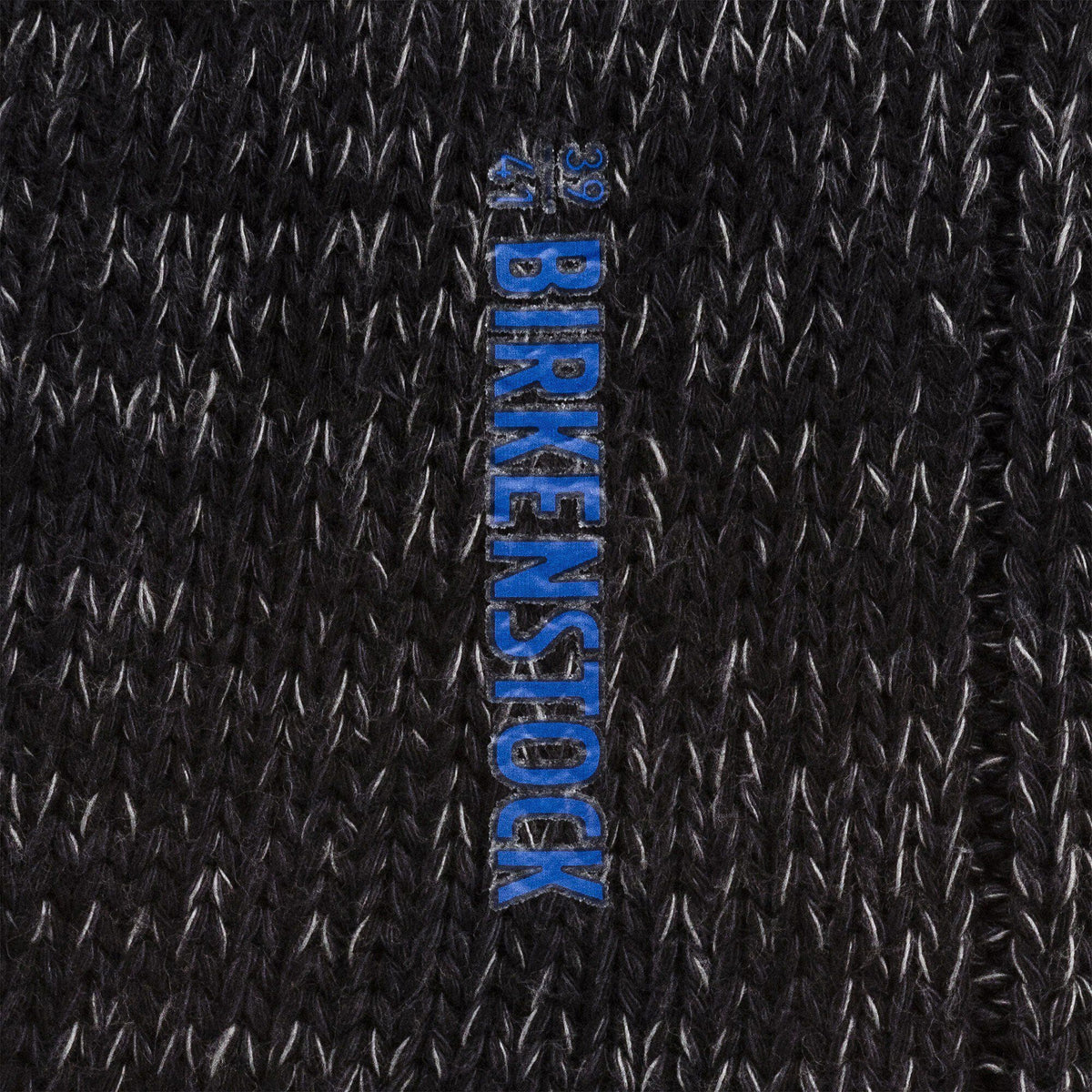 Close-up detail of black knit Birkenstock sock showing brand logo label with size markings