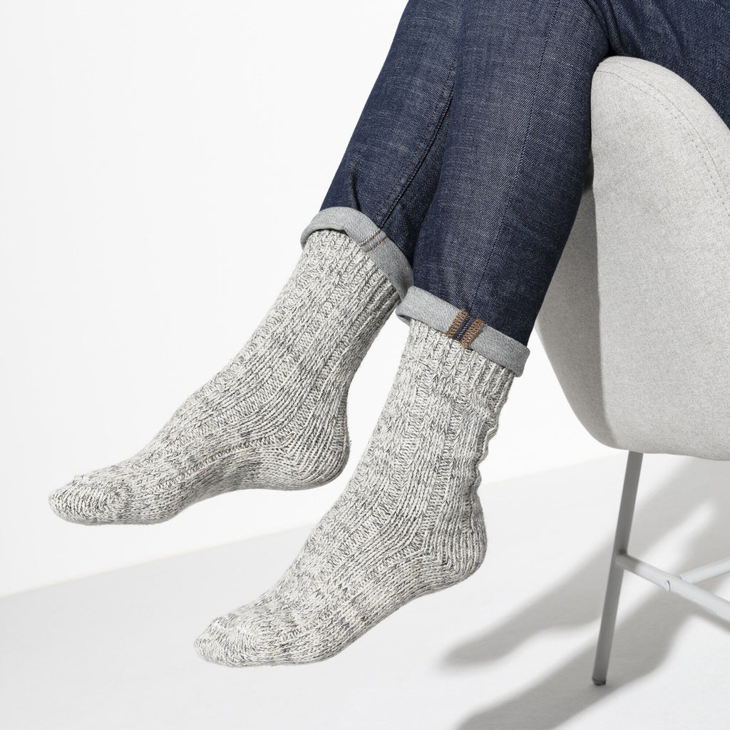 Person seated wearing light gray ribbed knit cotton crew socks with rolled denim jeans
