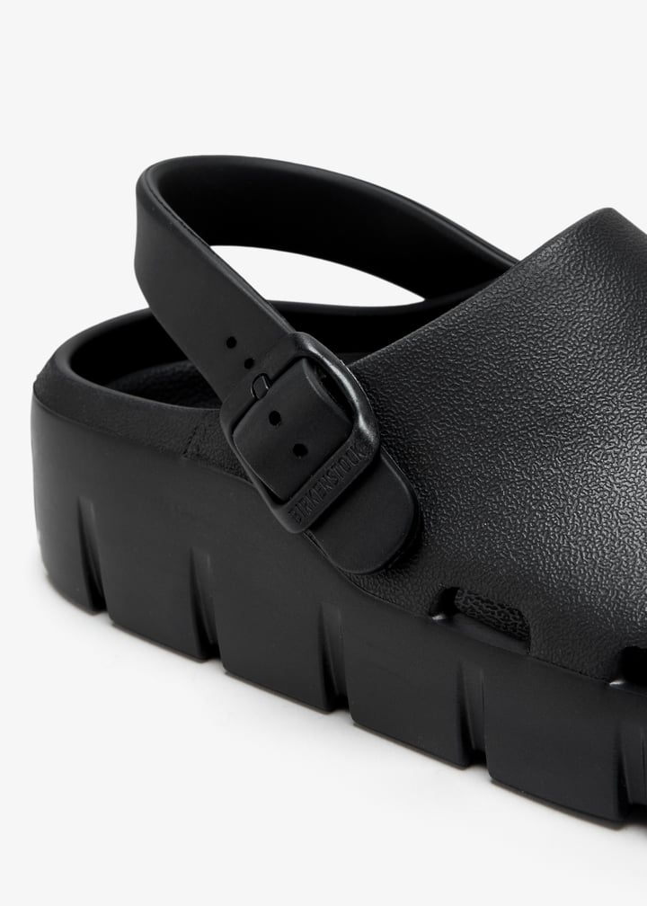 Close-up detail of black EVA sandal buckle strap and chunky lug sole platform