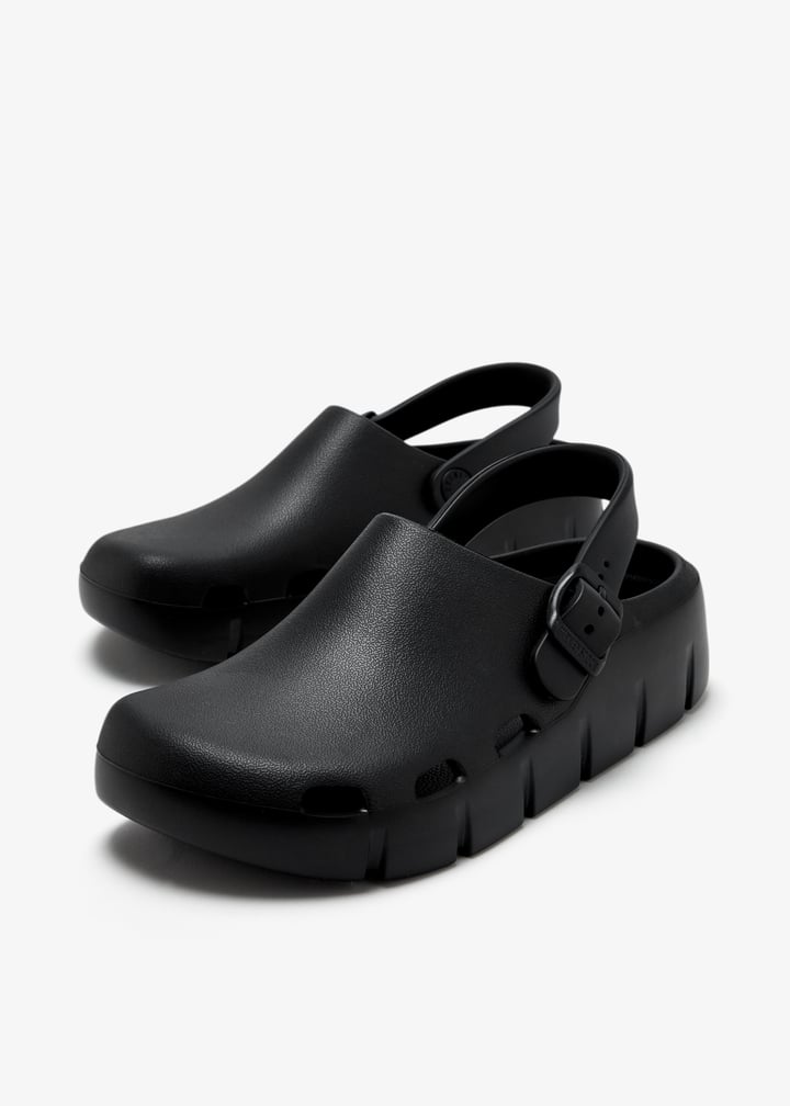 Pair of black EVA clogs with slingback strap and chunky textured sole, angled view