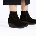 Women's suede wedge ankle boots with side zipper, worn with a midi skirt