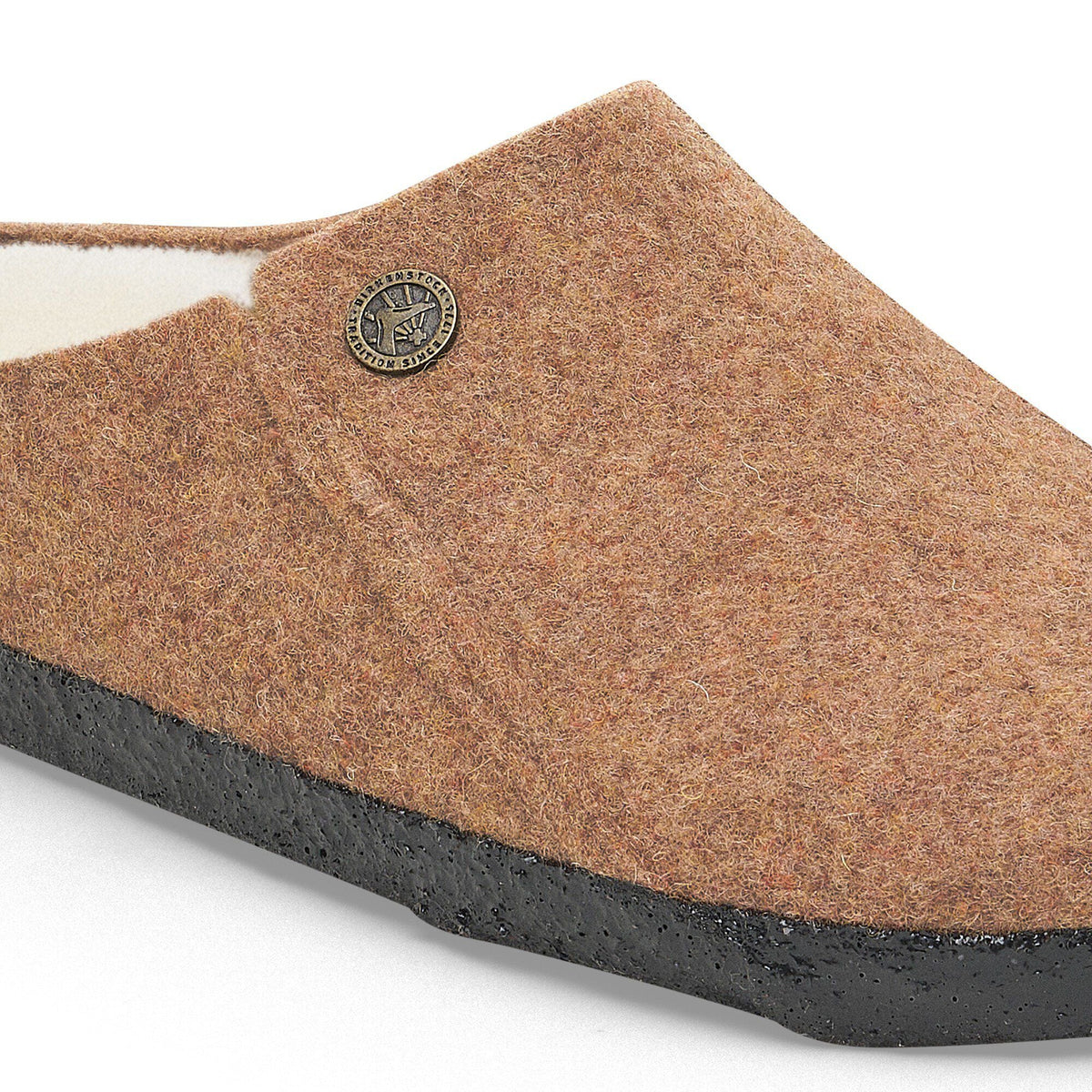 Close-up detail of a felted wool clog slipper with shearling lining and black rubber sole