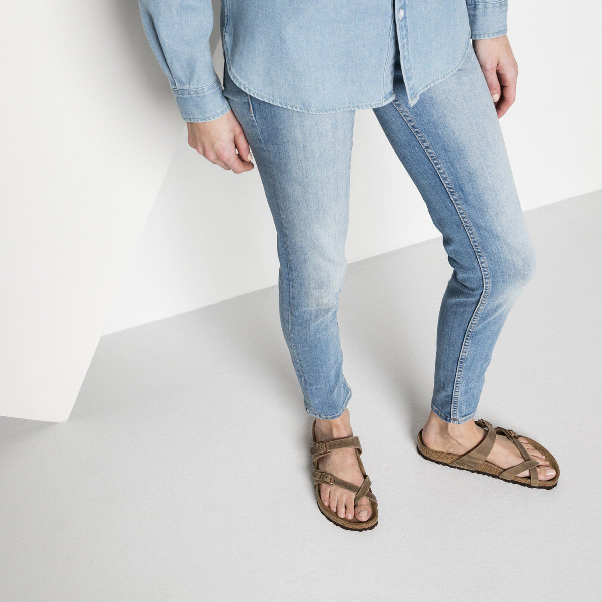 Woman wearing Birkenstock Mayari oiled leather sandals with skinny jeans and denim shirt