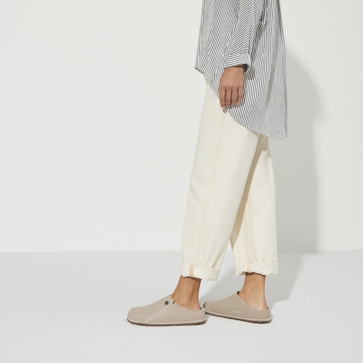 Model wearing Birkenstock Zermatt Canvas slip-on clogs styled with cream trousers and striped top