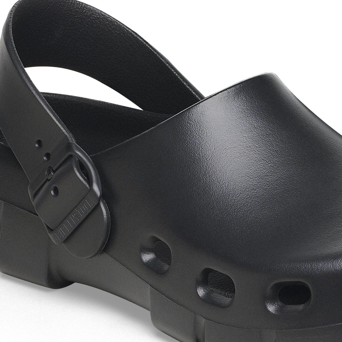 Close-up detail of a black clog sandal with ankle strap buckle and ventilation holes