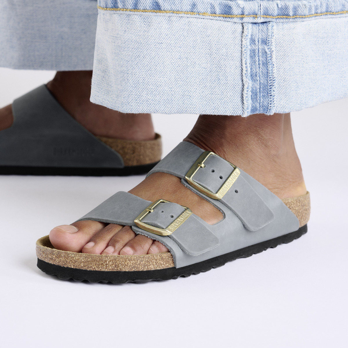 Birkenstock Arizona two-strap sandals with gold buckles worn with light denim skirt