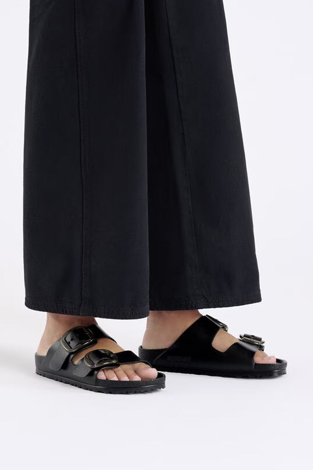 Model wearing black Birkenstock Arizona Big Buckle EVA sandals with wide-leg trousers