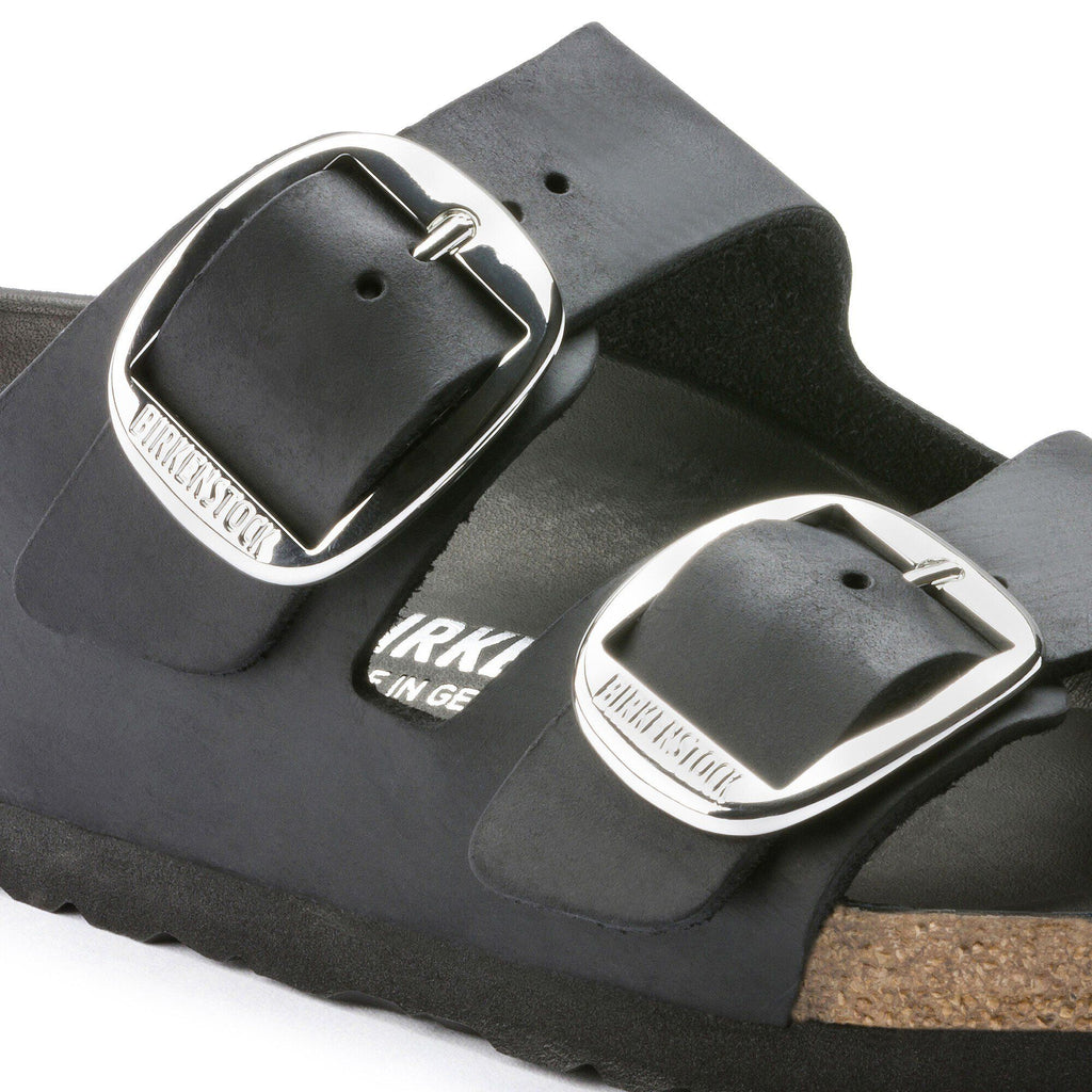 Close-up detail of Birkenstock Arizona sandal showing two large silver buckles on black leather straps