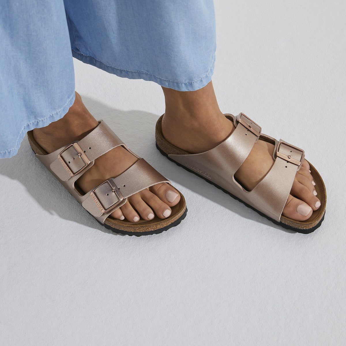 Birkenstock Arizona two-strap sandals worn on feet with light blue trousers