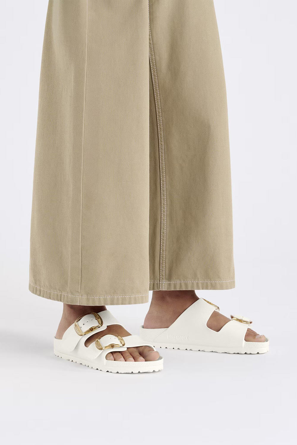 Model wearing white Birkenstock Arizona Big Buckle EVA sandals with wide-leg trousers