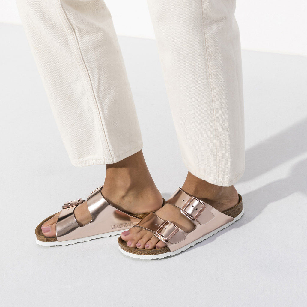 Model wearing metallic copper Birkenstock Arizona sandals with two buckle straps and white sole