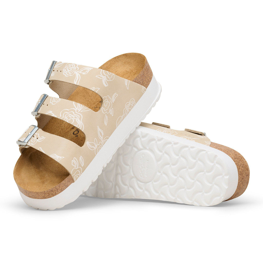Birkenstock platform sandals with two adjustable buckle straps and white floral pattern on beige upper