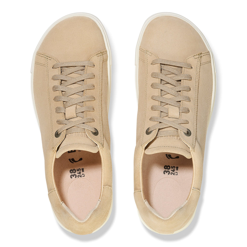 Top-down view of a pair of beige suede lace-up low-top sneakers with white soles