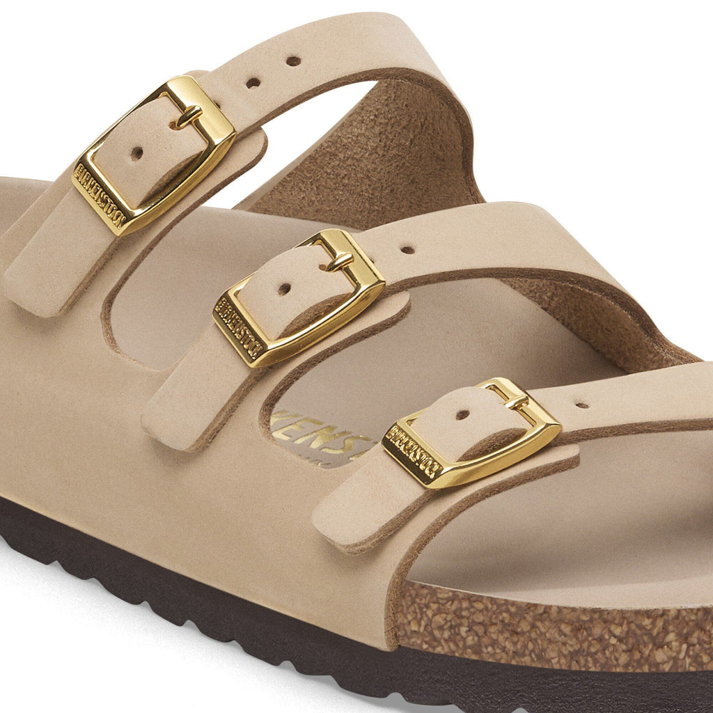 Close-up detail of Birkenstock three-strap sandal with gold buckles and cork footbed
