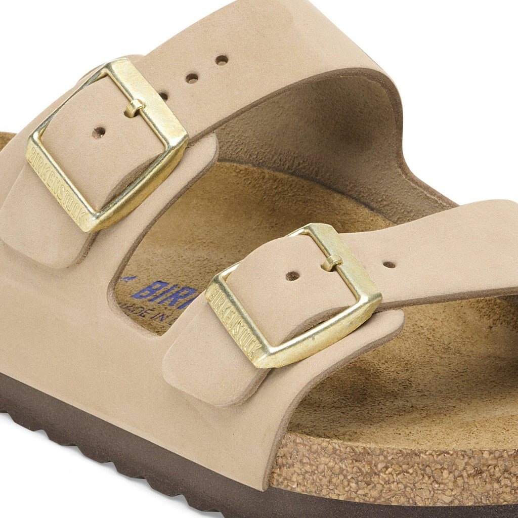 Close-up detail of Birkenstock Arizona sandal showing two gold buckles on nubuck leather straps