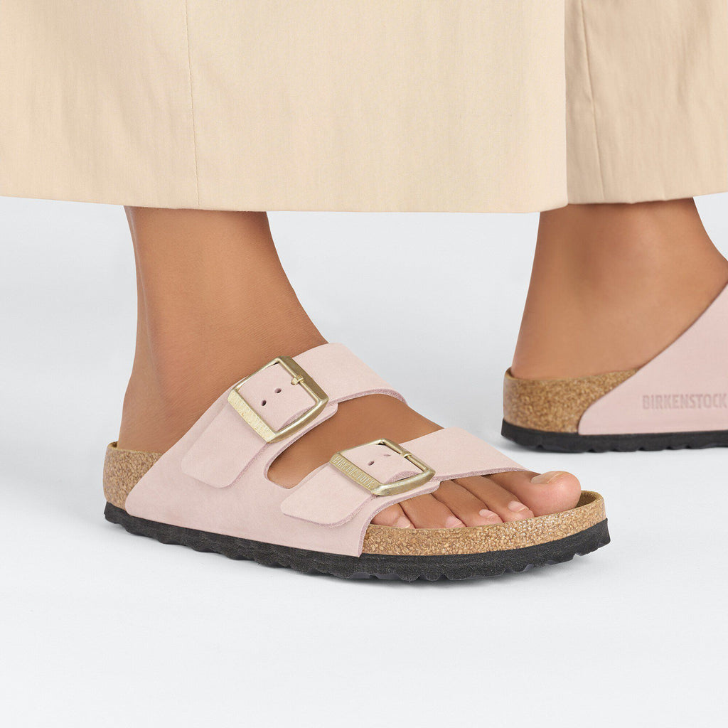 Model wearing Birkenstock Arizona two-strap sandals with gold buckles and cork footbed