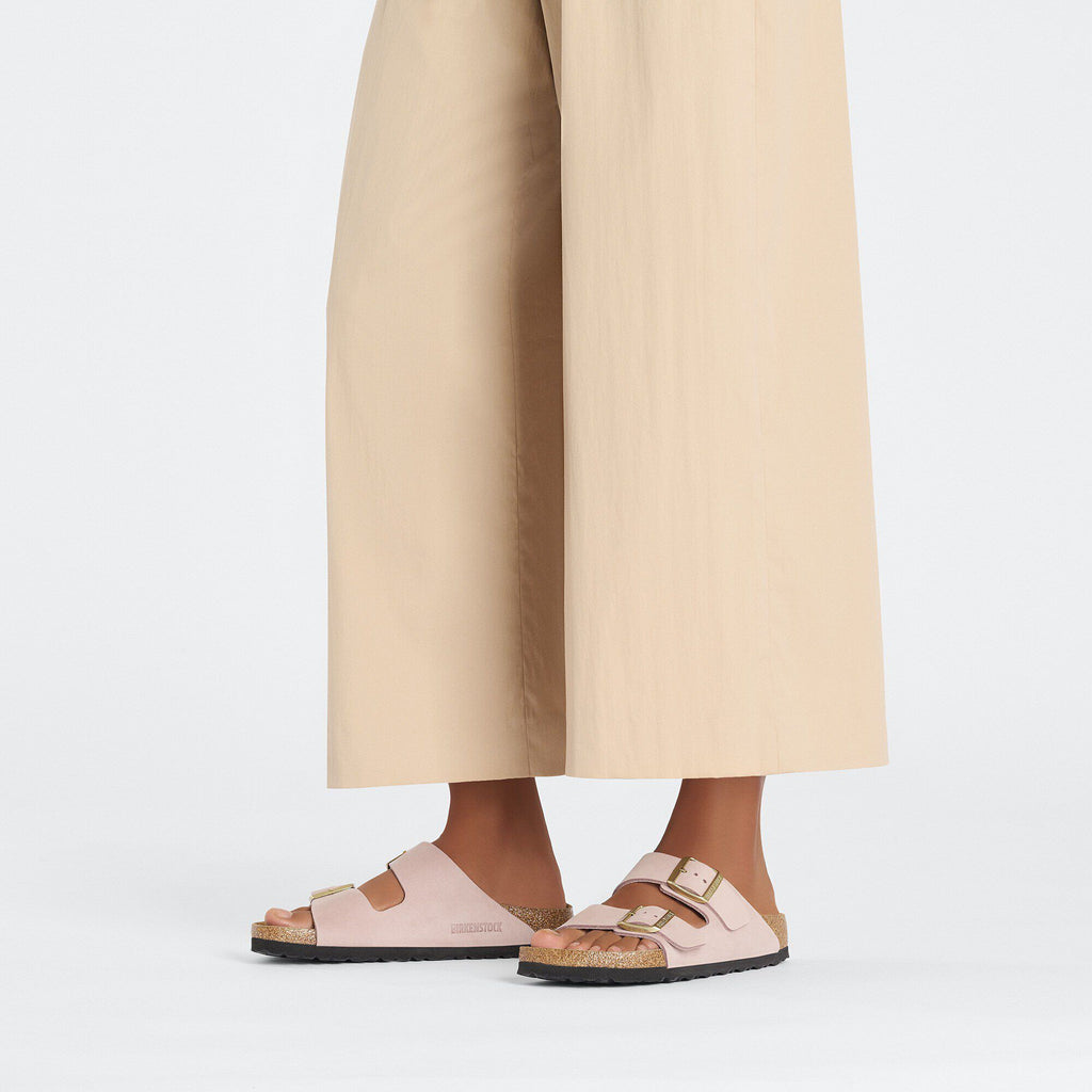 Model wearing Birkenstock Arizona double-strap sandals with gold buckles and cork footbed