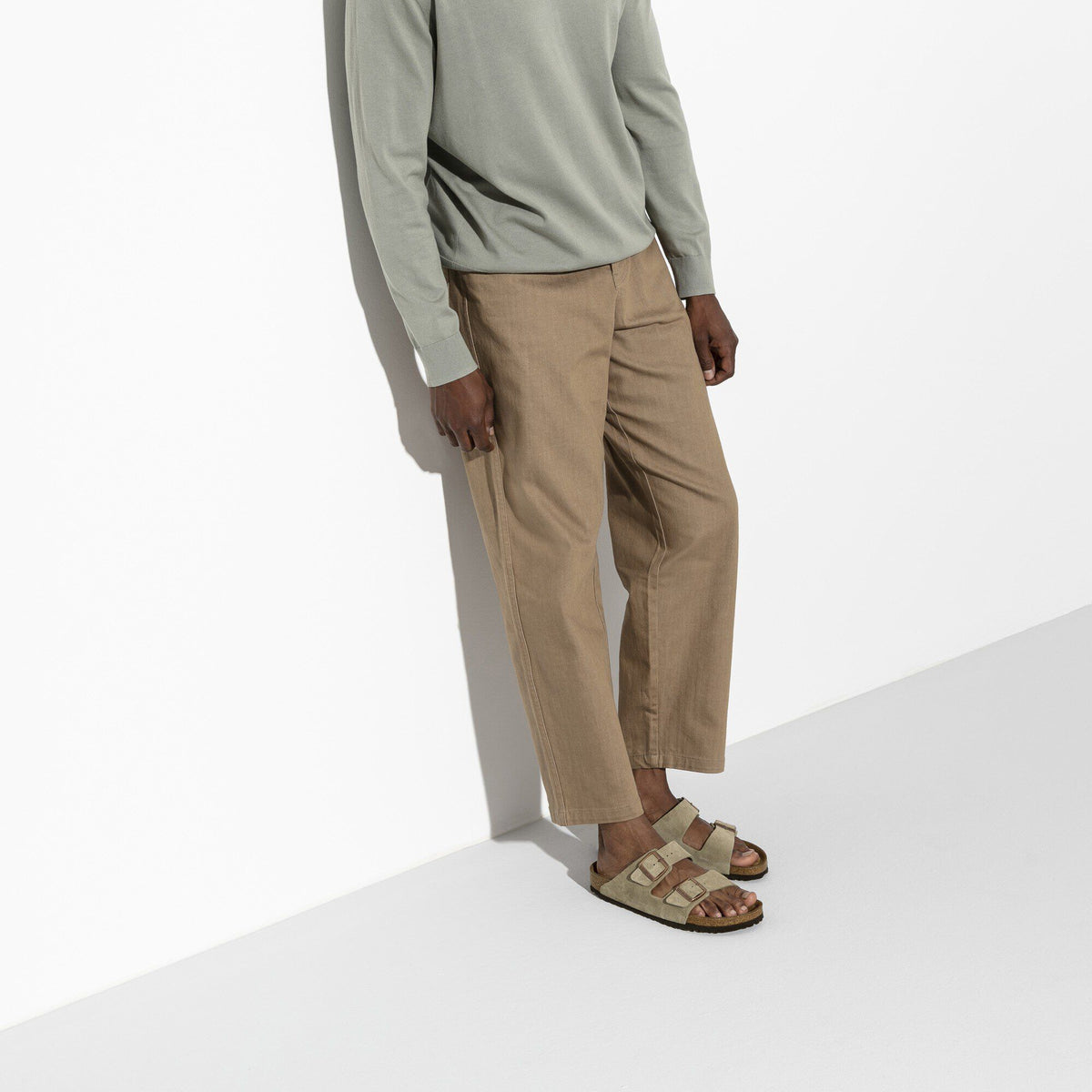 Model wearing Birkenstock Arizona suede sandals with two buckle straps paired with cropped trousers