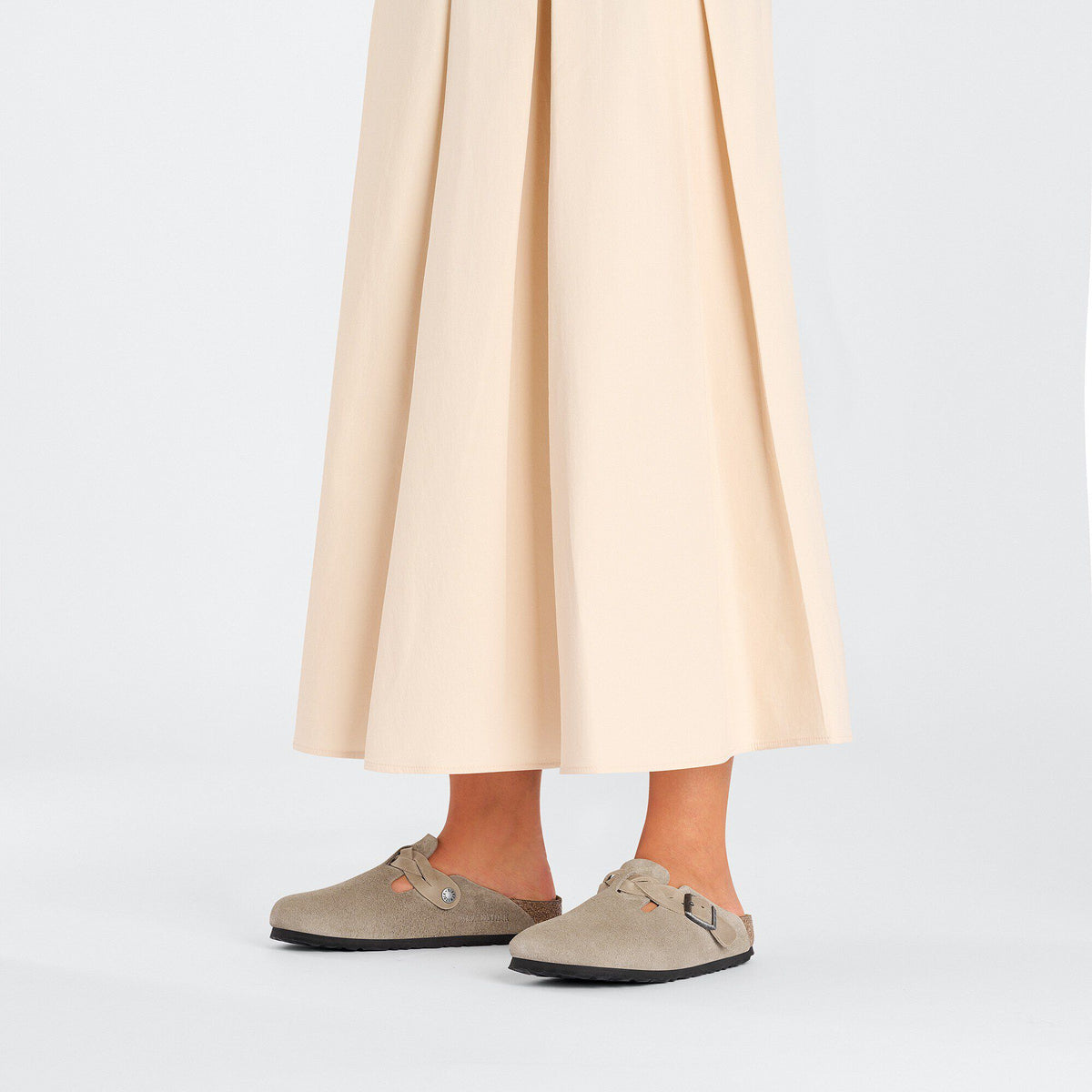 Woman wearing Birkenstock Boston Braid clogs with a flowing cream midi skirt