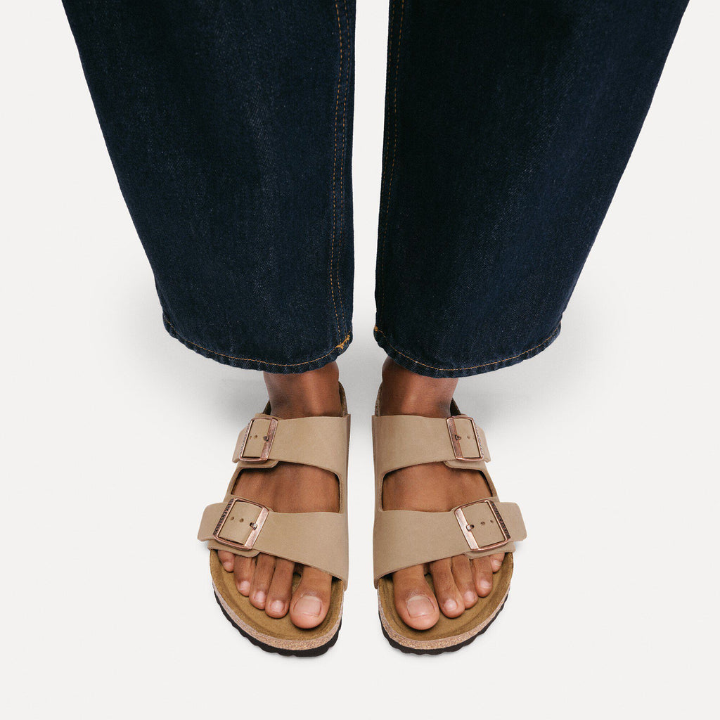 Birkenstock Arizona sandals with two buckle straps worn with dark denim jeans, overhead view