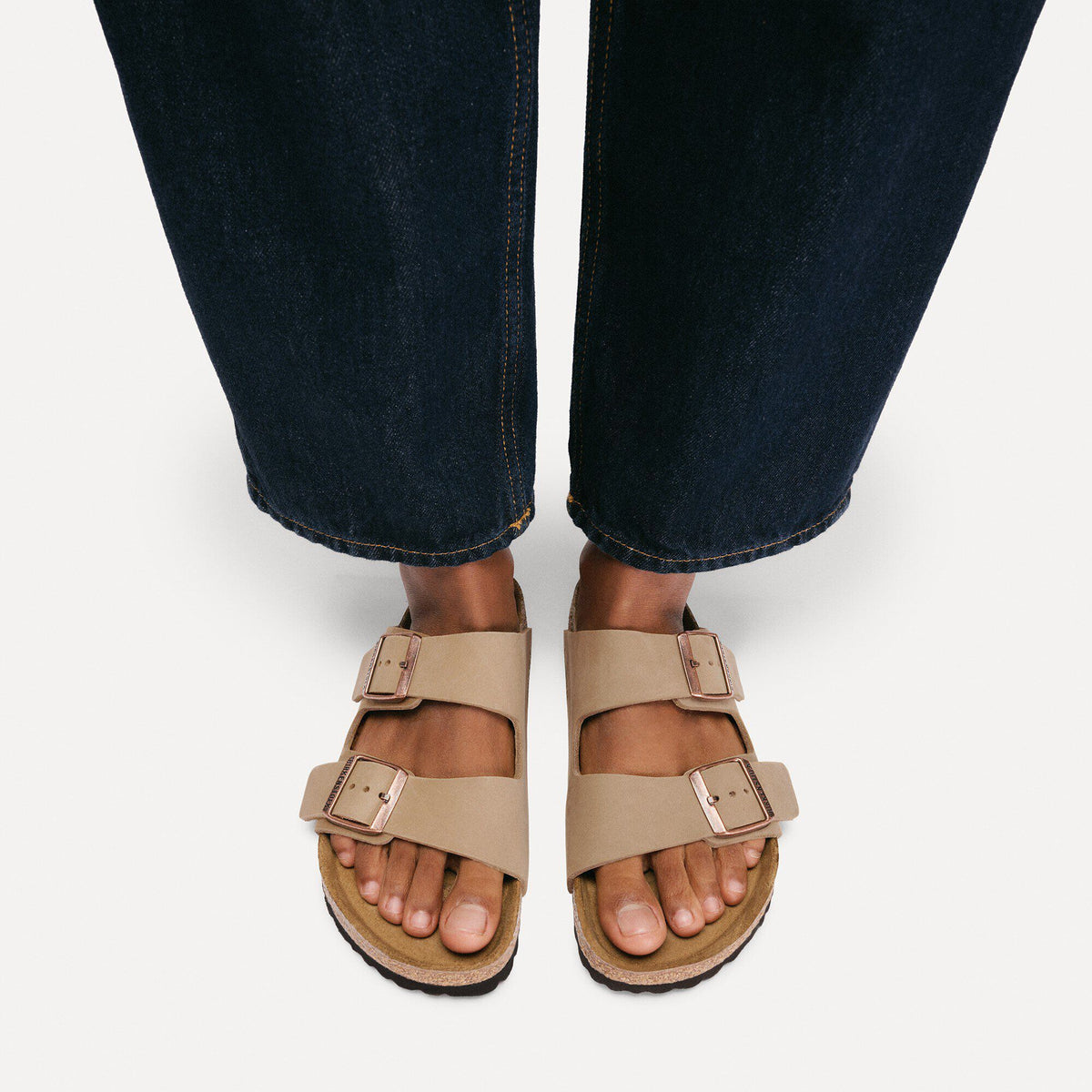 Birkenstock Arizona sandals with two buckle straps worn with dark denim jeans, overhead view