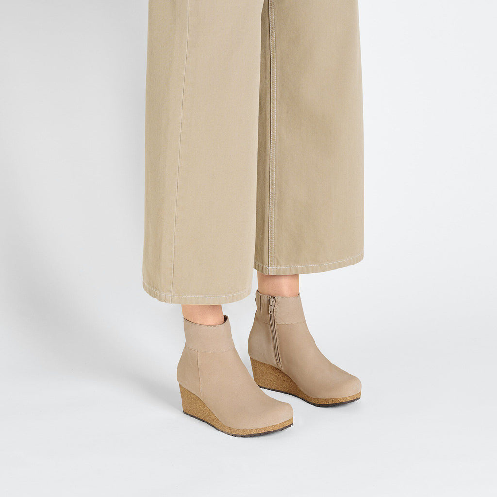 Women's wedge ankle boots with cork sole and side zipper, styled with wide-leg trousers