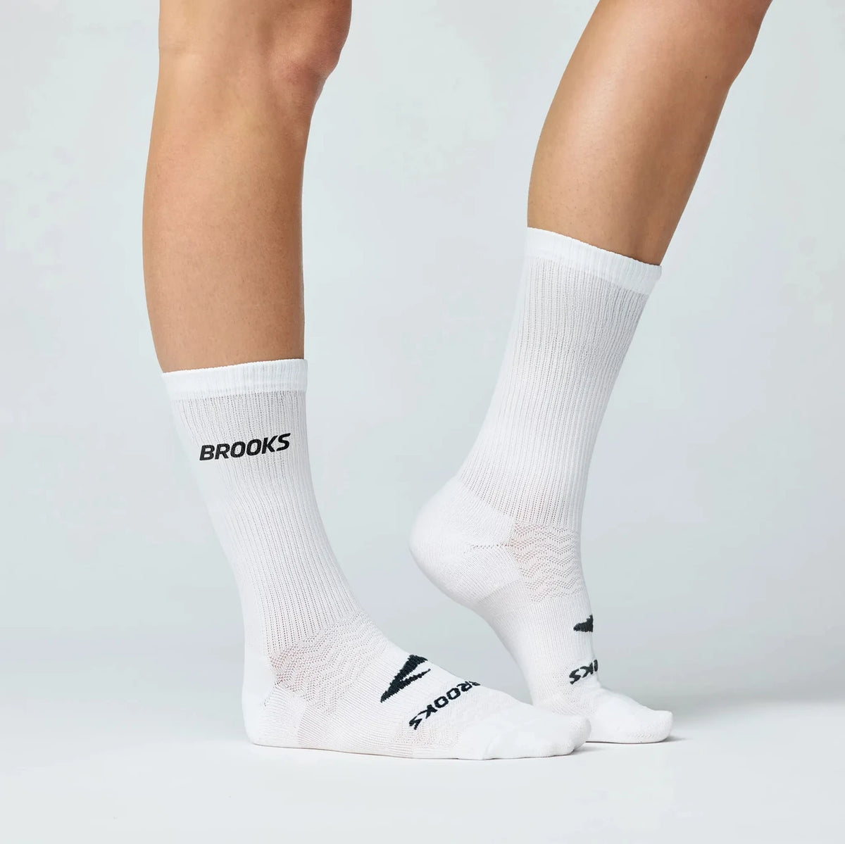 Brooks crew running socks in white shown on model legs from two angles