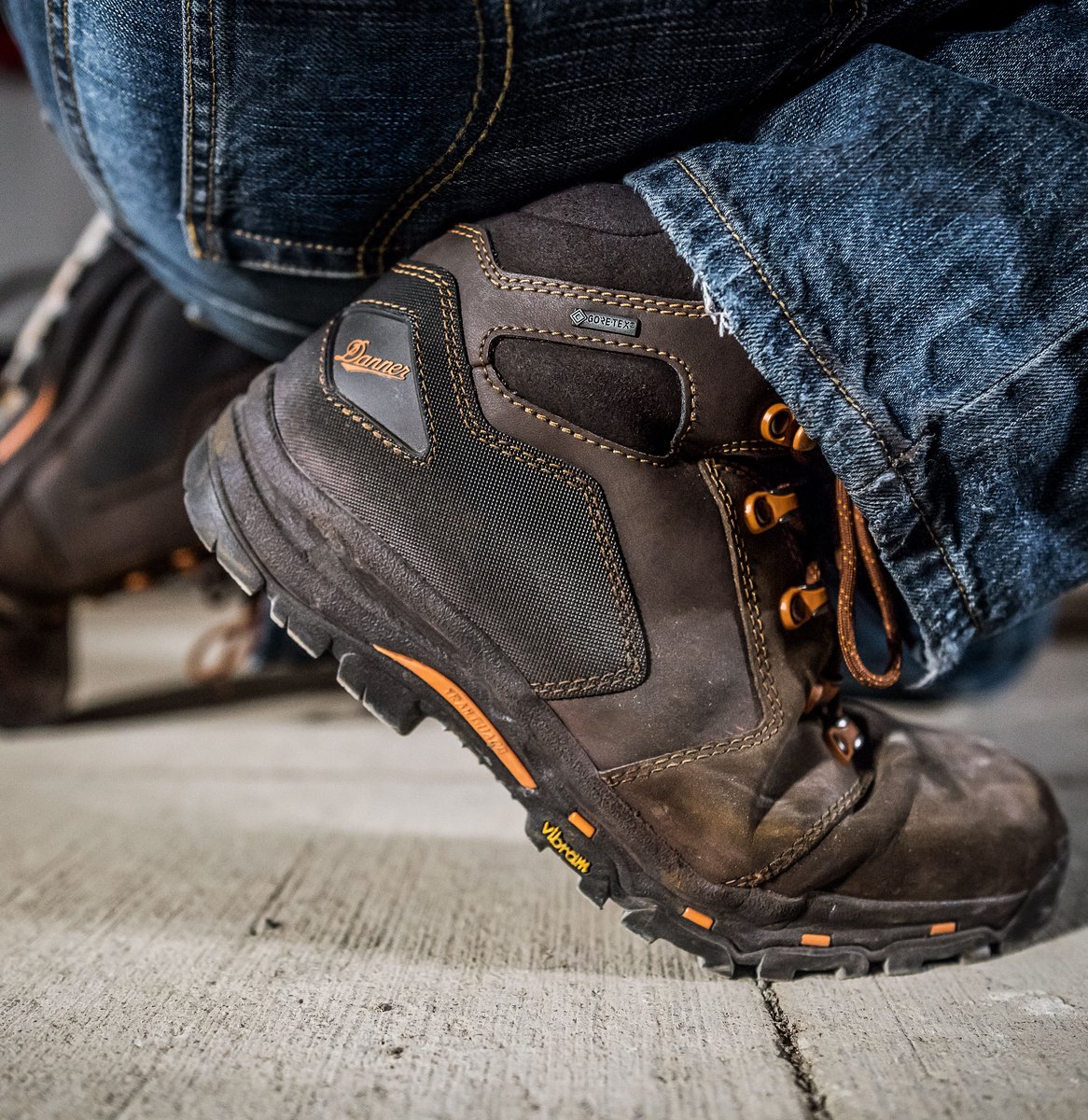 Danner men's mid work boot with orange laces and Vibram outsole worn with jeans