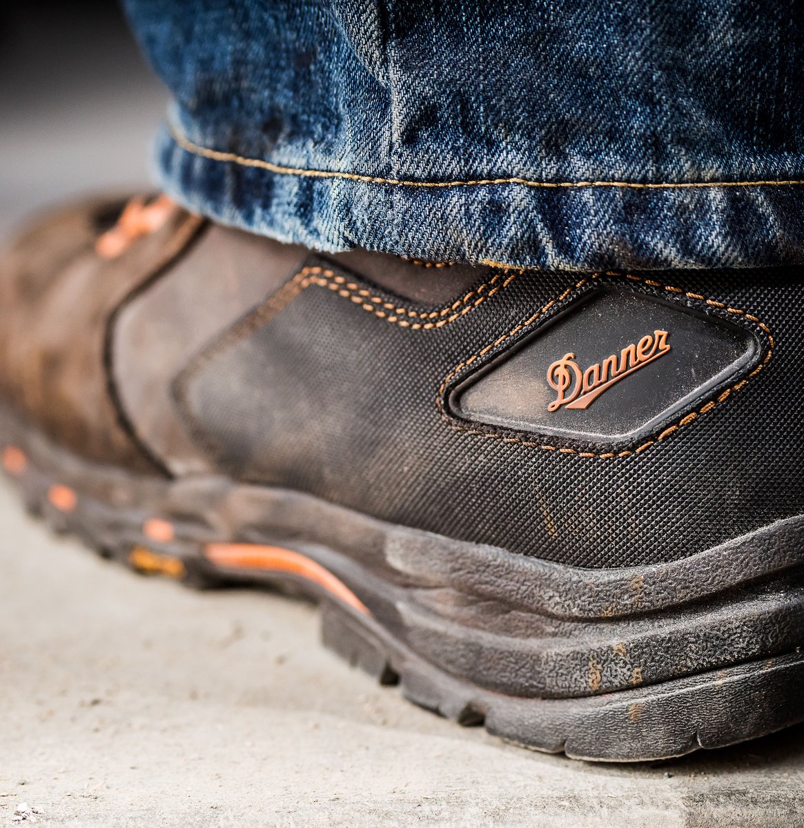 Close-up detail of Danner work boot heel and logo badge worn with jeans
