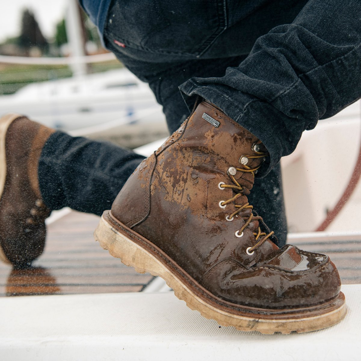 Danner men's lace-up moc toe work boots worn on a wet boat deck