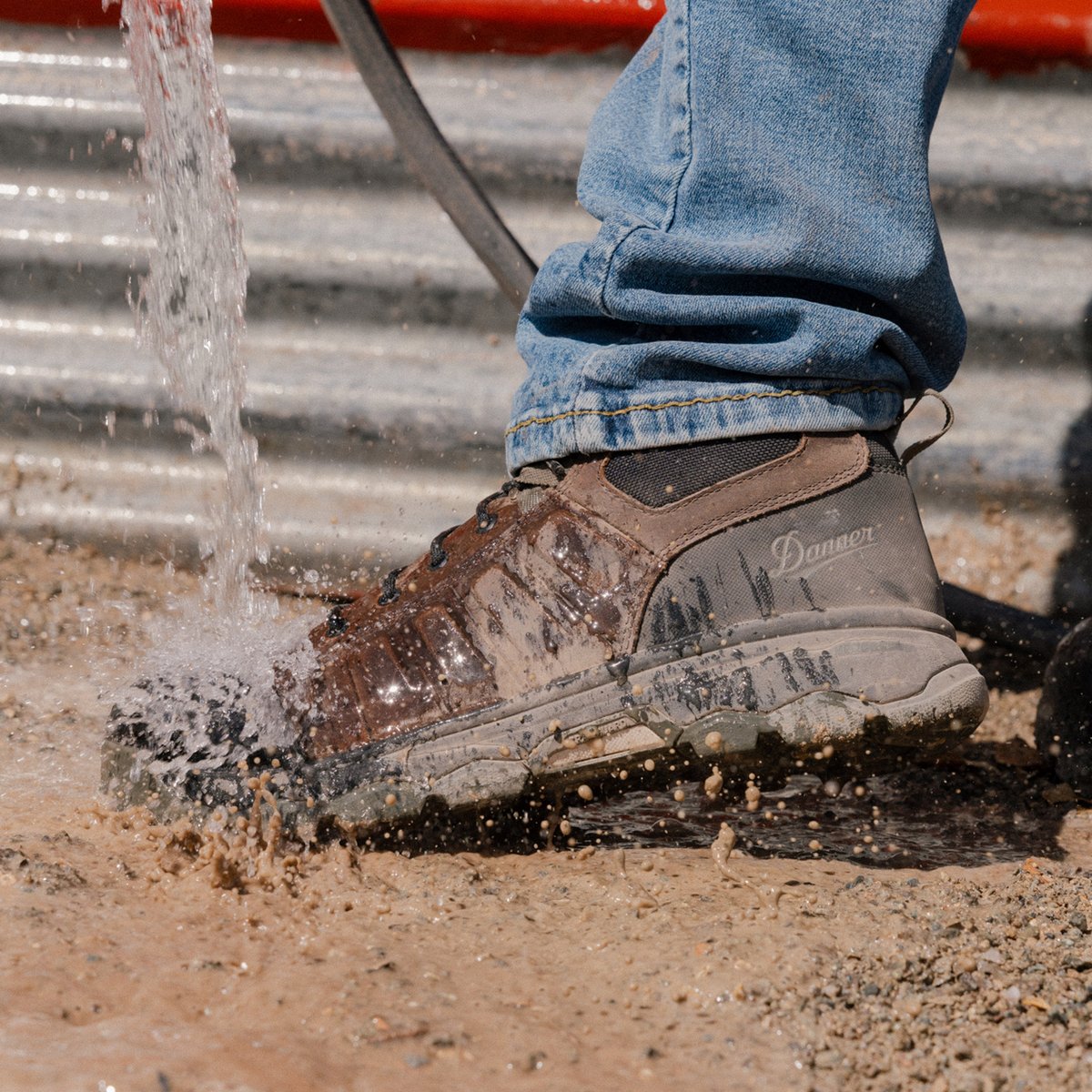 Danner men's hiking boot being splashed with water in muddy outdoor work setting