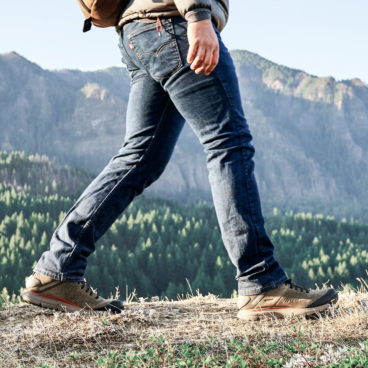 Person hiking on mountain ridge wearing Danner Trail mid hiking shoes with rugged outsoles