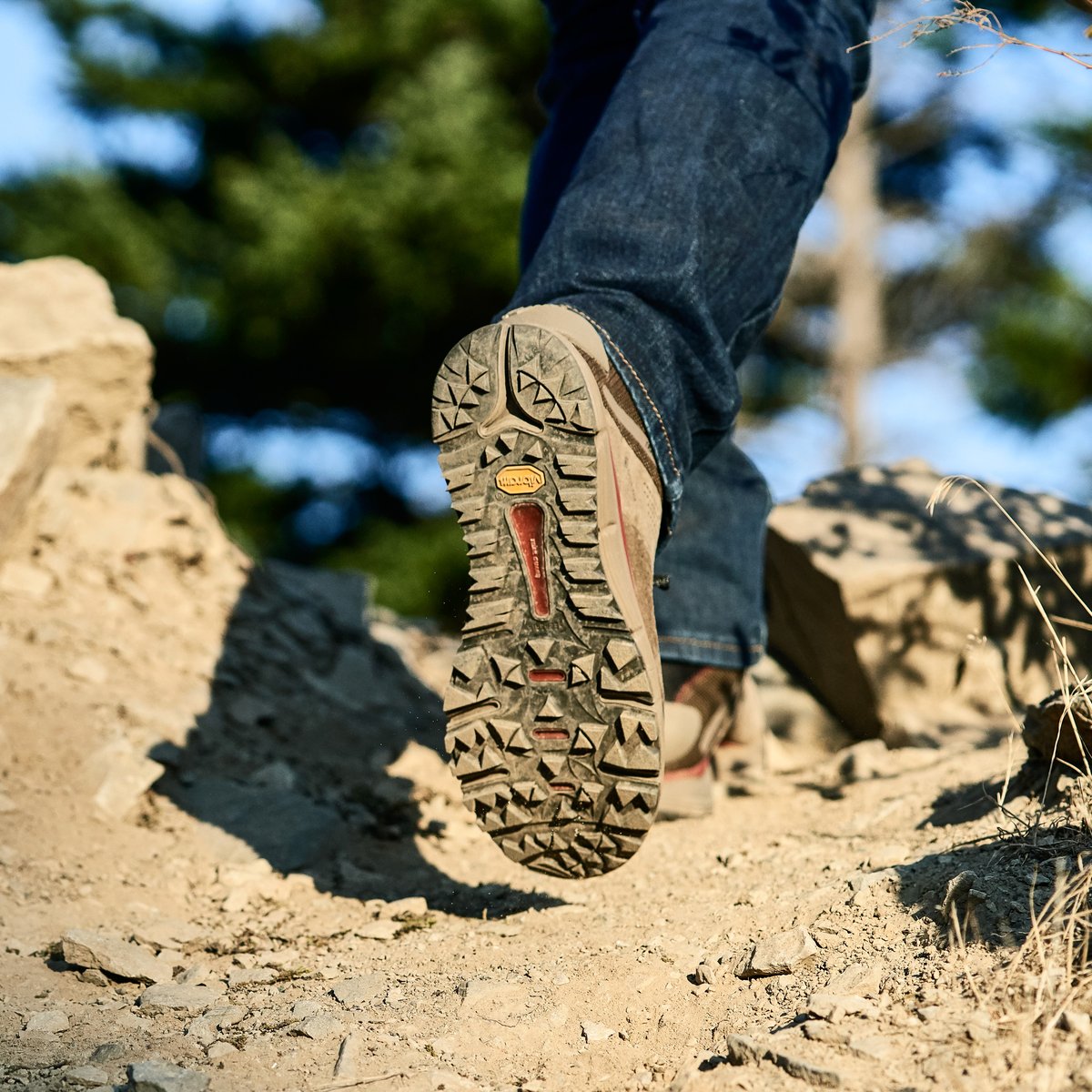 Close-up of Danner hiking boot sole stepping over rocky terrain on outdoor trail