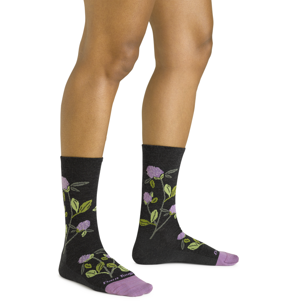 Woman wearing dark charcoal crew socks with purple floral and green leaf pattern