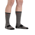 Model wearing gray and black Darn Tough boot socks with red mountain logo, front view