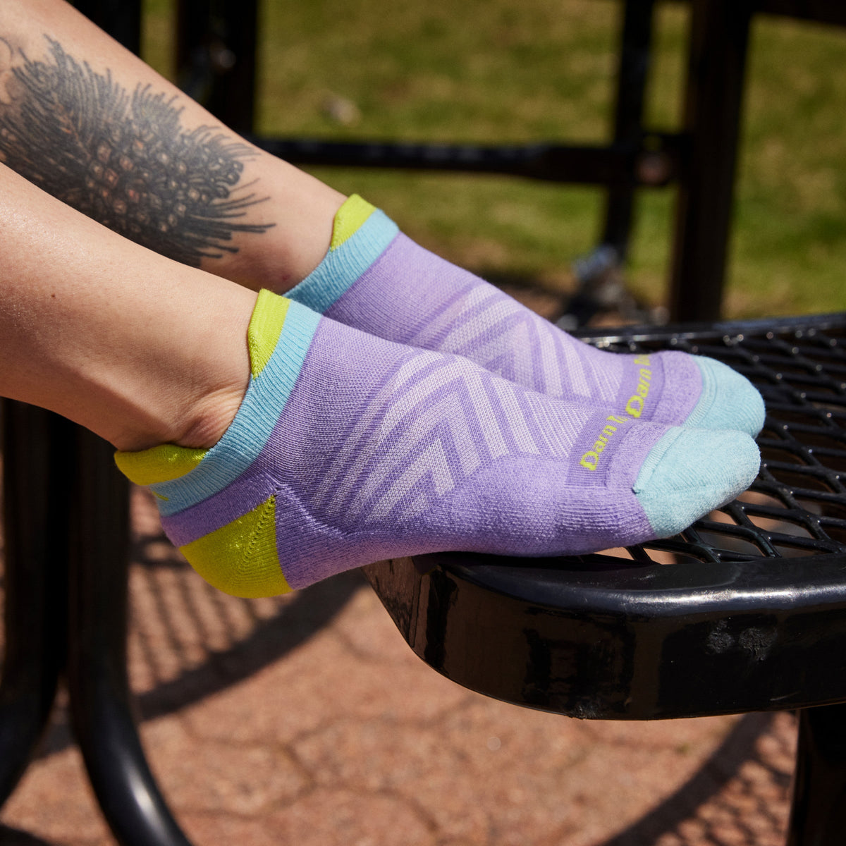 Close-up of feet resting on outdoor chair wearing colorful no-show running tab socks