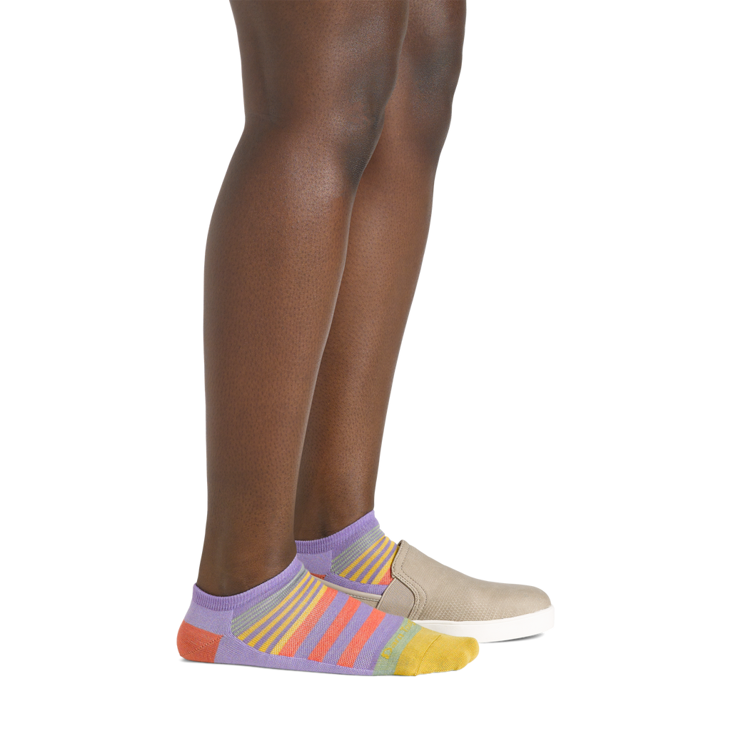 Side view of legs wearing lavender rainbow-striped no-show socks with casual slip-on shoes
