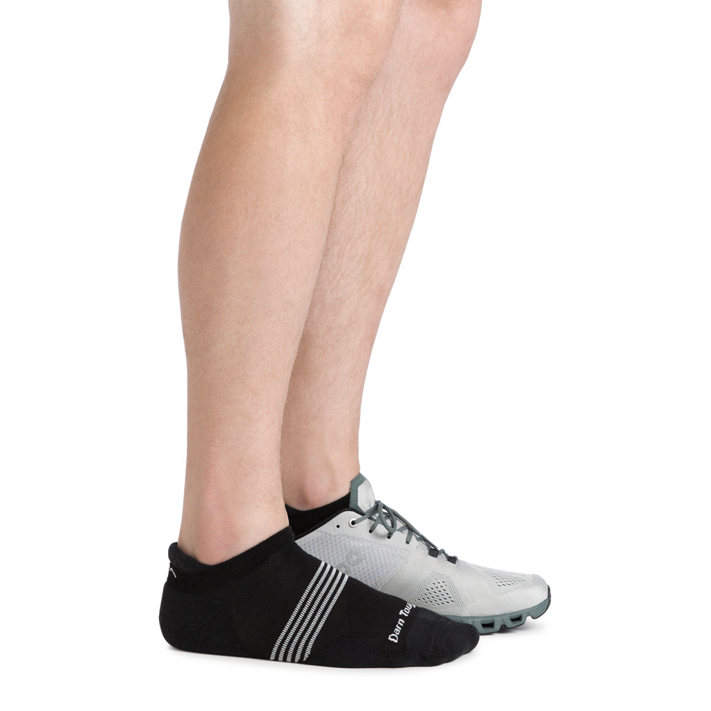 Close-up of legs wearing black Darn Tough no-show tab socks with gray athletic shoes