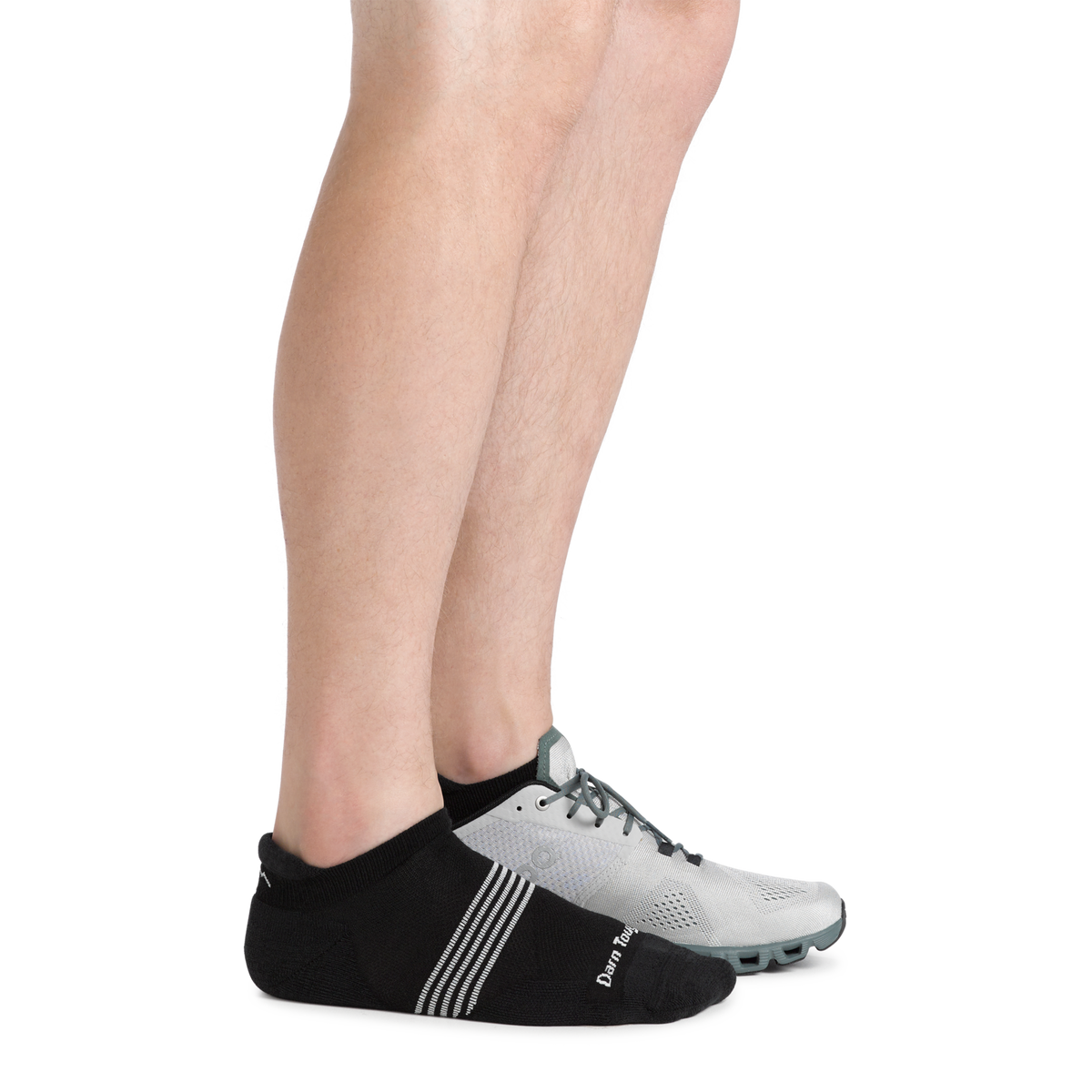Close-up of legs wearing black Darn Tough no-show tab socks with gray athletic shoes