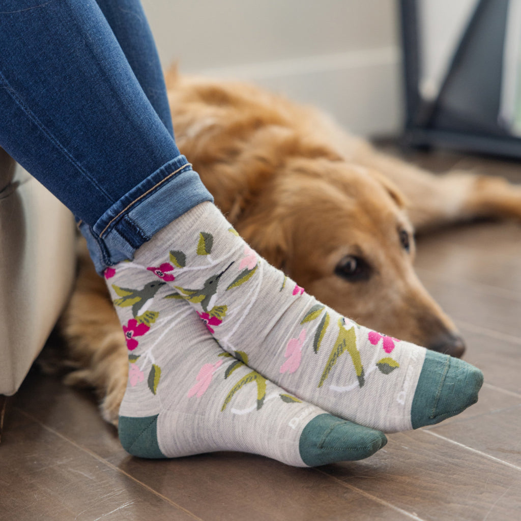 Woman wearing floral crew socks with teal toe and heel beside a golden retriever