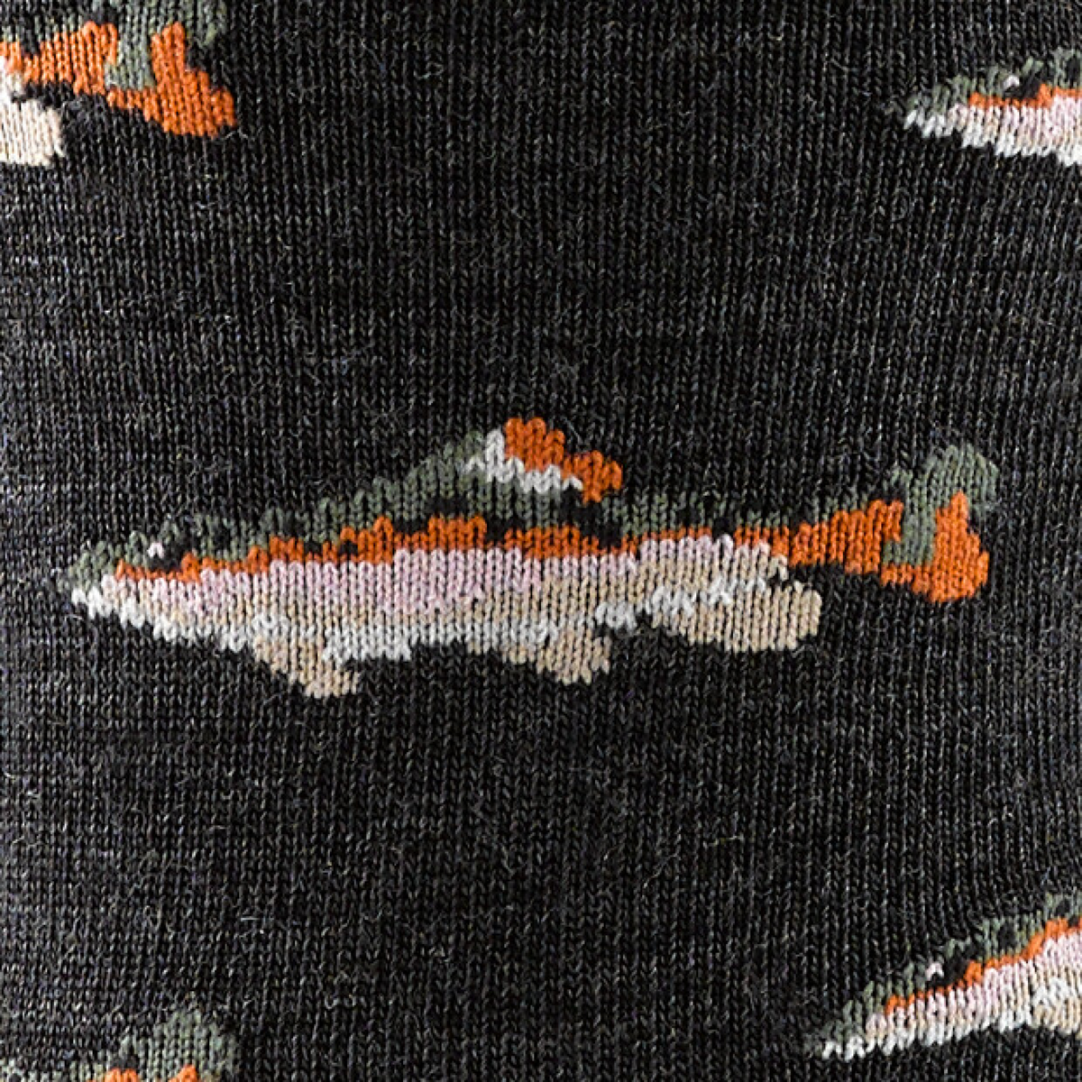 Close-up knit detail of men's crew sock featuring fish pattern on dark background