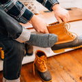 Person putting on duck boots while wearing Darn Tough mid-calf gray socks
