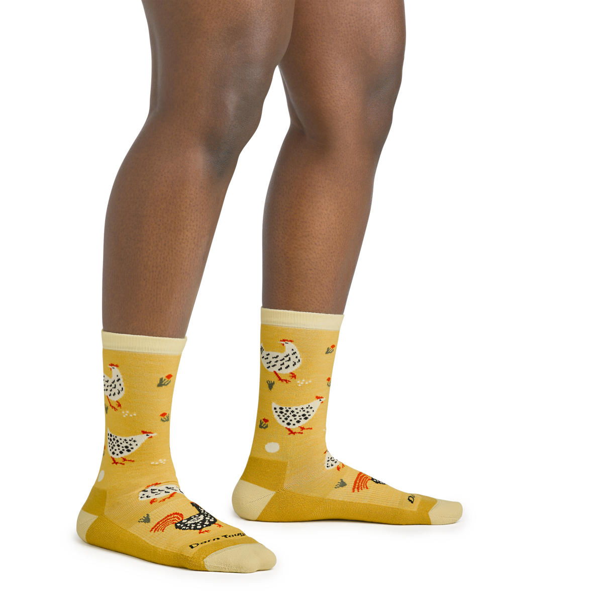 Model wearing yellow crew socks featuring illustrated chickens and roosters pattern on legs