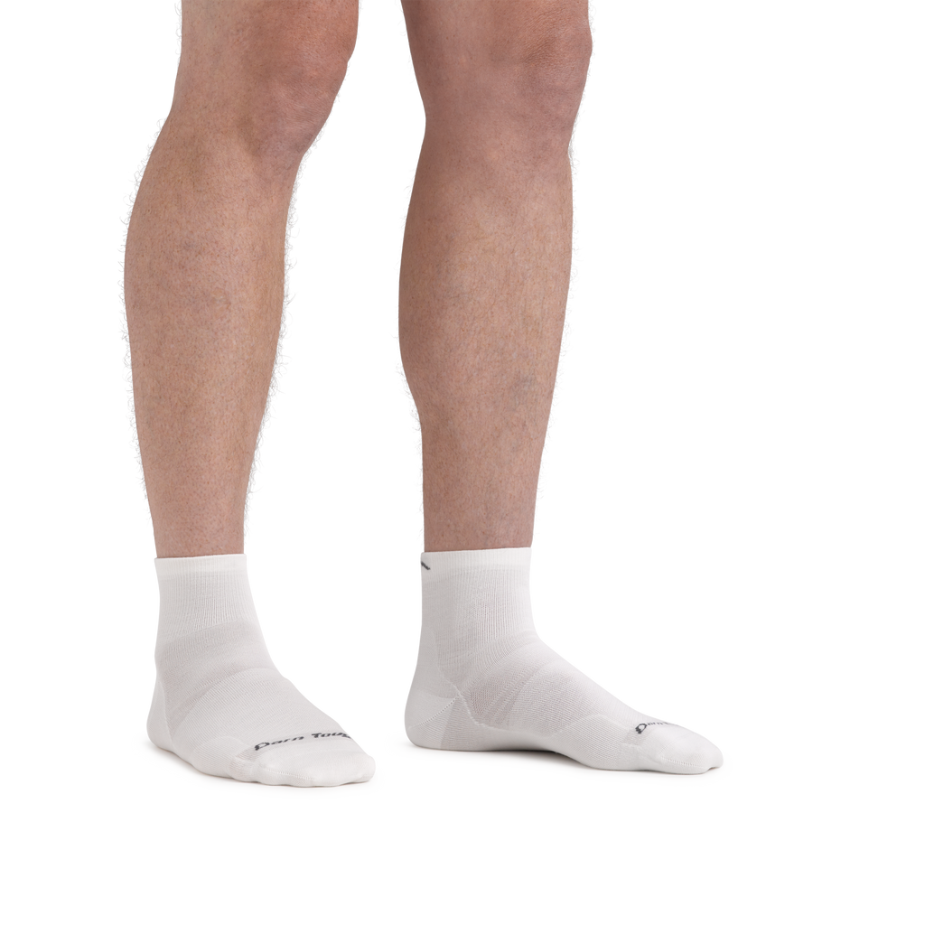 Model wearing Darn Tough quarter-length running socks shown from knees down on both feet